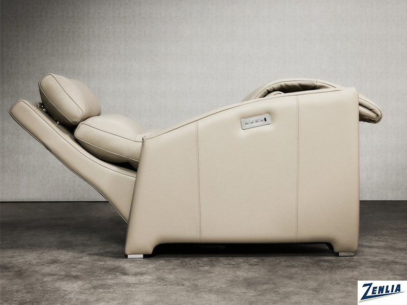 A sleek, beige recliner is fully extended, showcasing its modern design against a neutral background, with a visible brand logo on the side.
